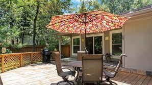 Une terrasse en bois avec une table et des chaises, un parasol et un barbecue.