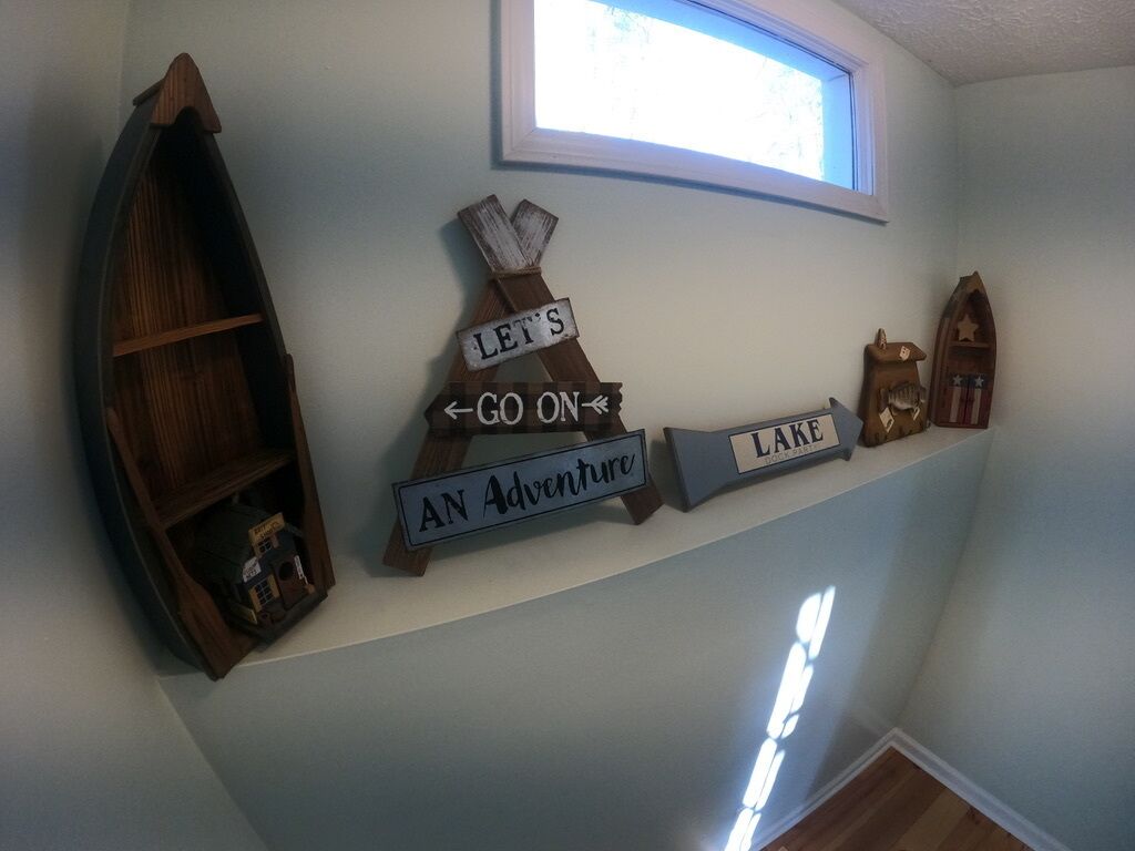 A wall with a wooden boat shelf, a sign that says "LET'S GO ON AN ADVENTURE," and a small wooden boat decoration.
