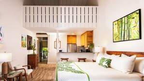 Ein Hotelzimmer mit Bett, Schreibtisch, Stuhl, Küchenzeile und Esstisch.