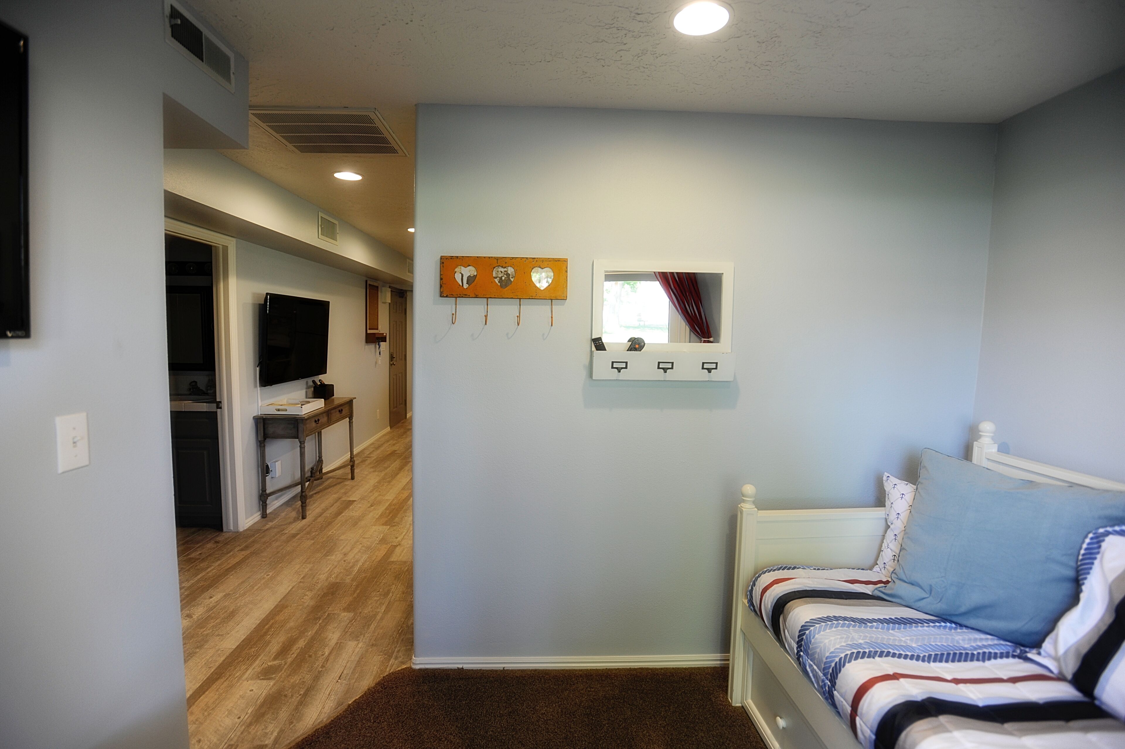 A bedroom with a bed, a small table, and a mirror on the wall.
