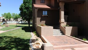 A residential building with a brick exterior, a covered porch, and a small garden area with a pathway and steps leading to the entrance.