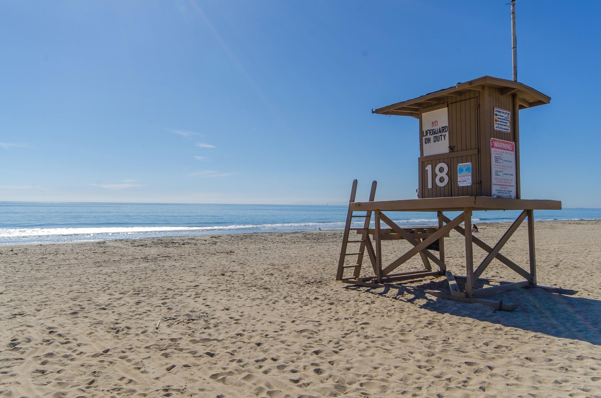 Una torre de socorrista en una playa con cielos despejados.