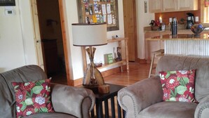 A cozy living room with two grey sofas, a wooden coffee table, and a bulletin board on the wall. -  Secluded Mountainside Cabin, Close to Town, No 4 wheel drive needed!  Hot Tub! (Bryson City)