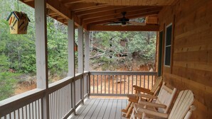 A wooden porch with rocking chairs, a ceiling fan, and a view of the forest. -  Secluded Mountainside Cabin, Close to Town, No 4 wheel drive needed!  Hot Tub! (Bryson City)