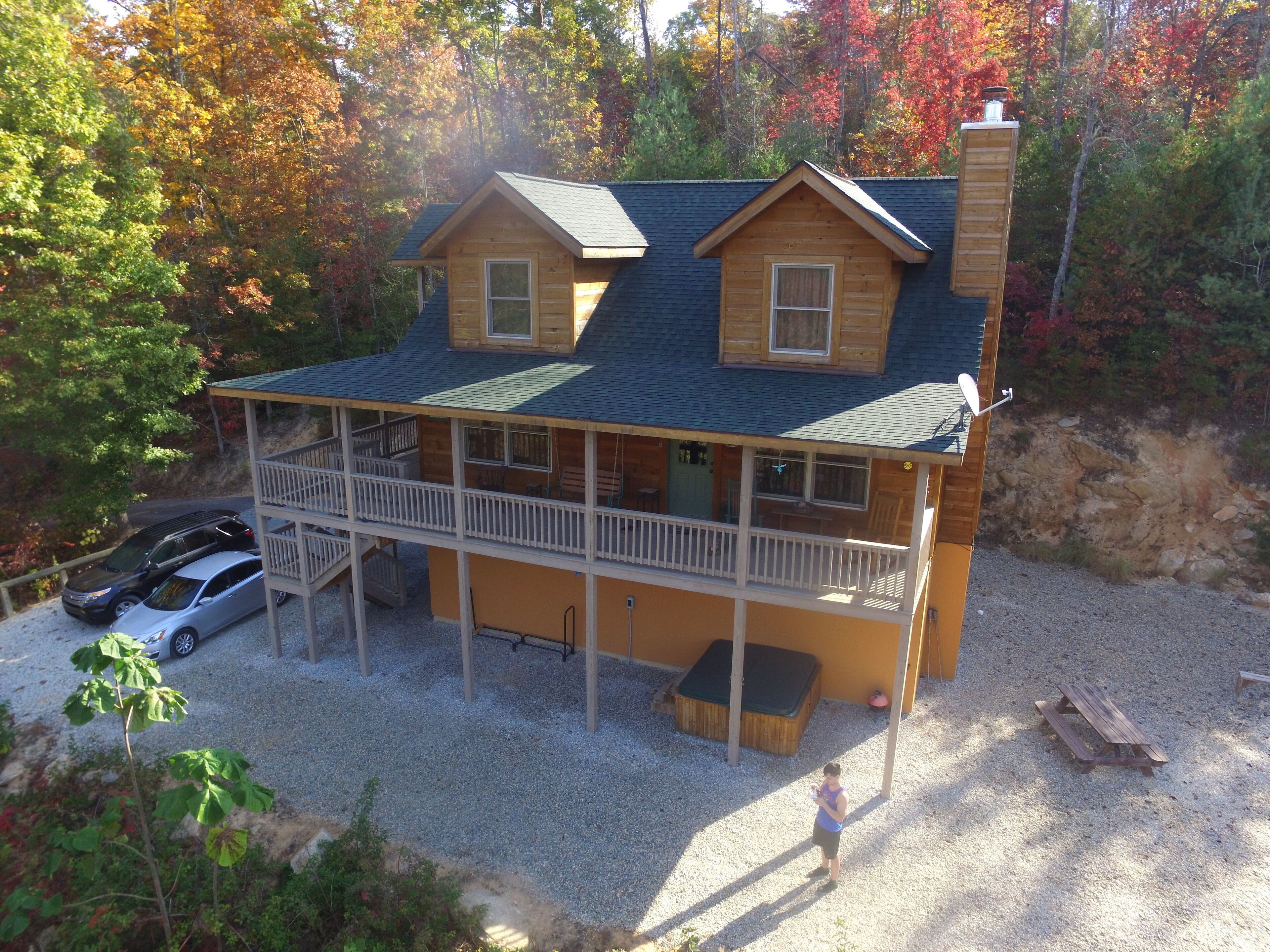 Une cabane à deux étages dotée d’un balcon, d’une véranda et d’un bain à remous.