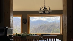 Una cocina con un ventanal grande, muebles de madera y una lámpara colgante.