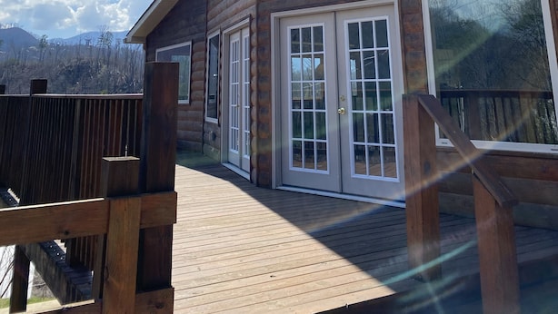 Una cabaña de madera con ventanas grandes y una terraza.