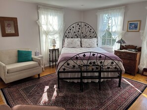 Un dormitorio con cama, mesita de noche, cómoda, sofá y ventana con cortinas.