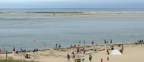 A beach with people, a sign, and a body of water.