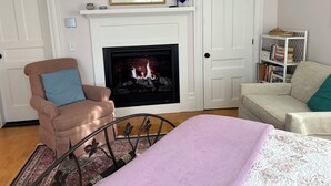 A living room with a fireplace, a bookshelf, and two sofas. - Chatham Village - Adorable Studio Apartment in Antique Home (Chatham)