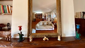 Un miroir avec un cadre décoratif, une étagère en bois avec des livres et une petite figurine d’éléphant.
