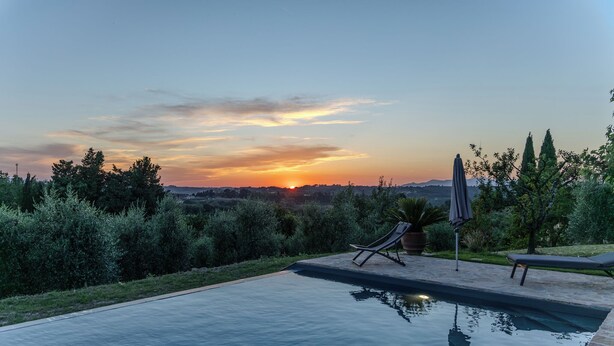 Une piscine avec des chaises longues et une vue sur le coucher de soleil.