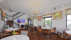 Amplia sala de estar con escaleras, varias mesas de comedor y asientos cómodos.