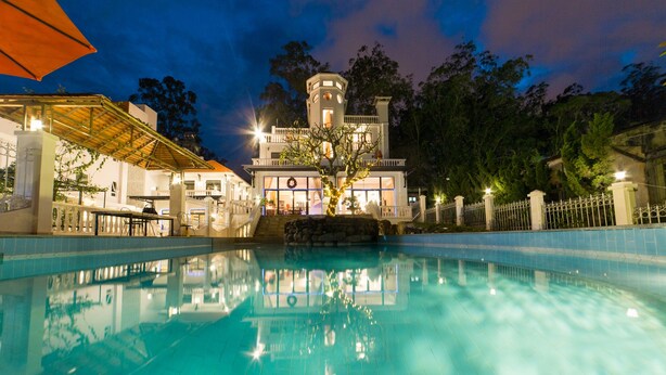 Piscina que refleja un edificio y árboles.