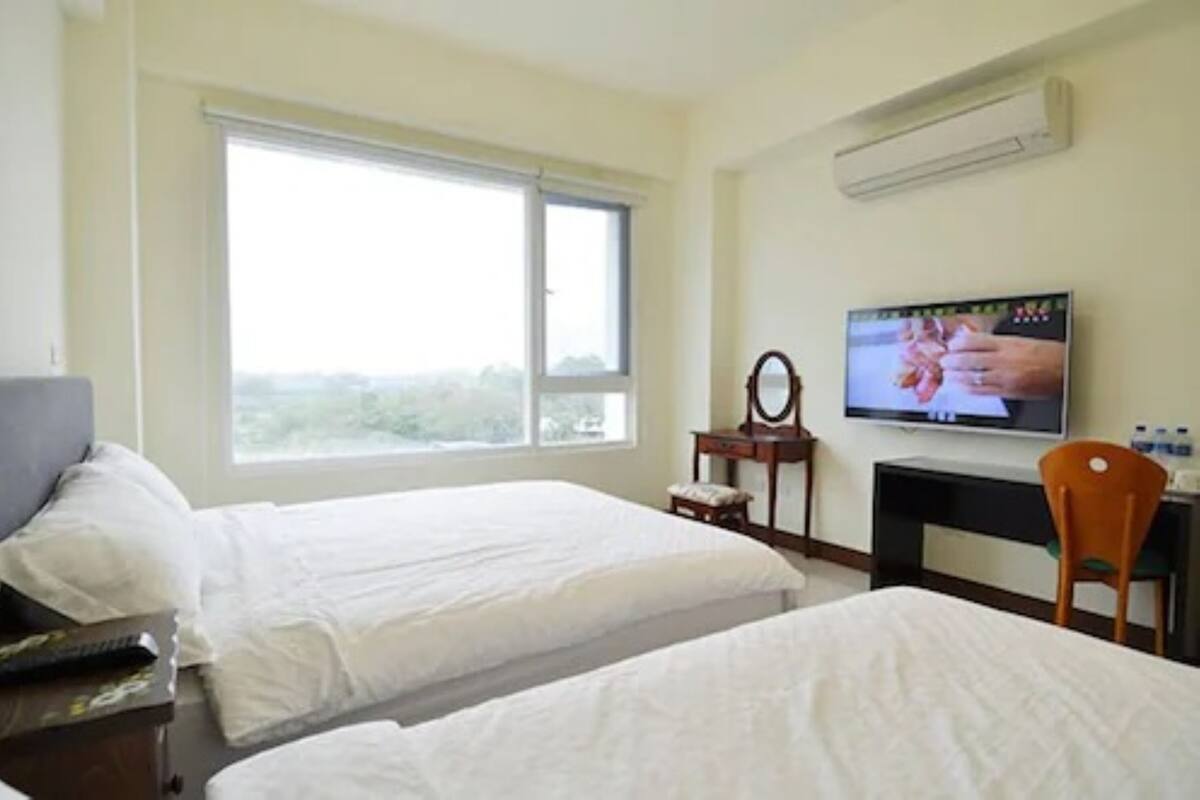 A hotel room with two beds, a TV, a desk, and a chair.