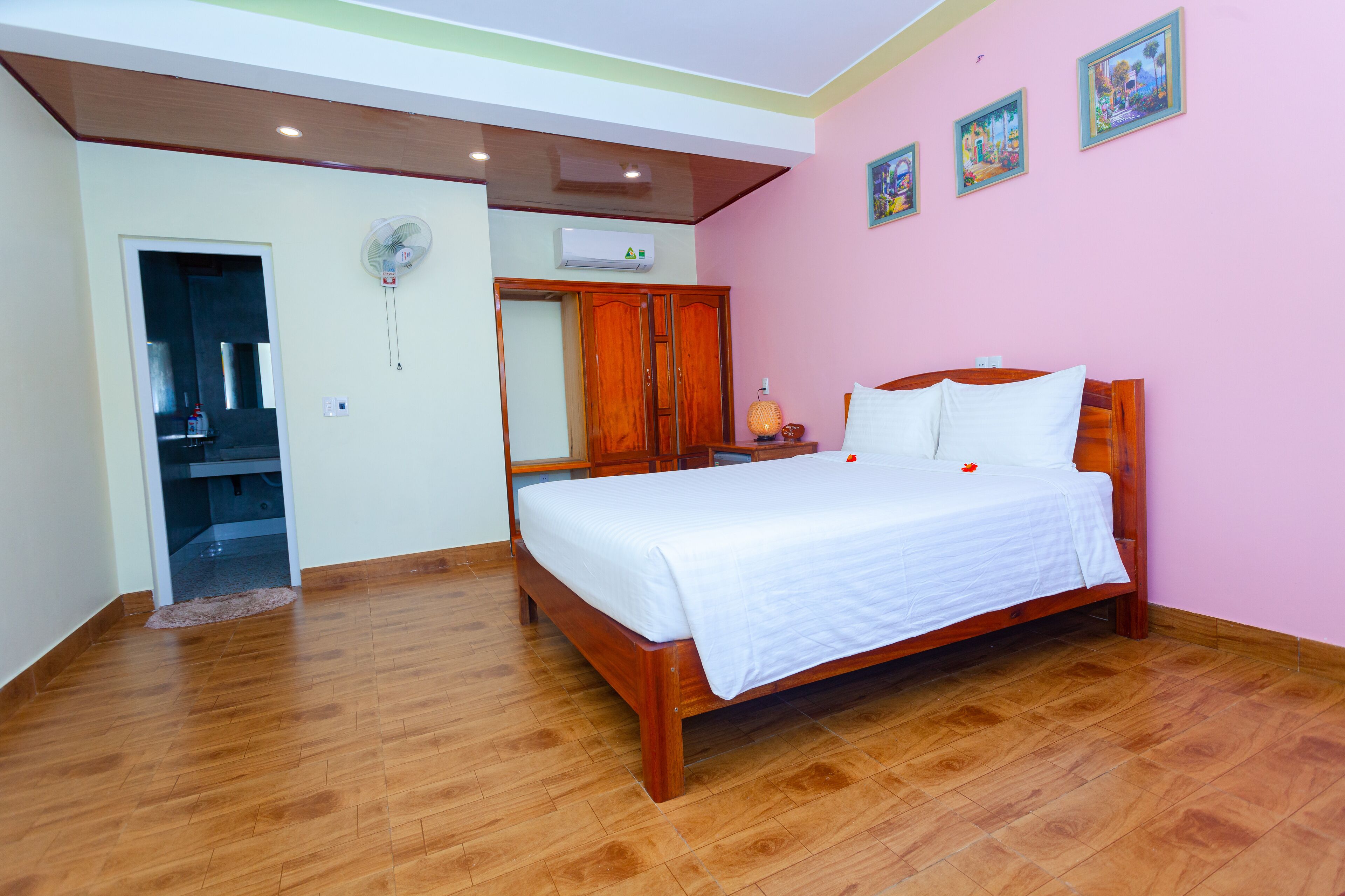 A bedroom with a wooden bed, a wardrobe, a mirror, and a ceiling fan.