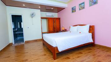 A bedroom with a wooden bed, a wardrobe, a mirror, and a ceiling fan.