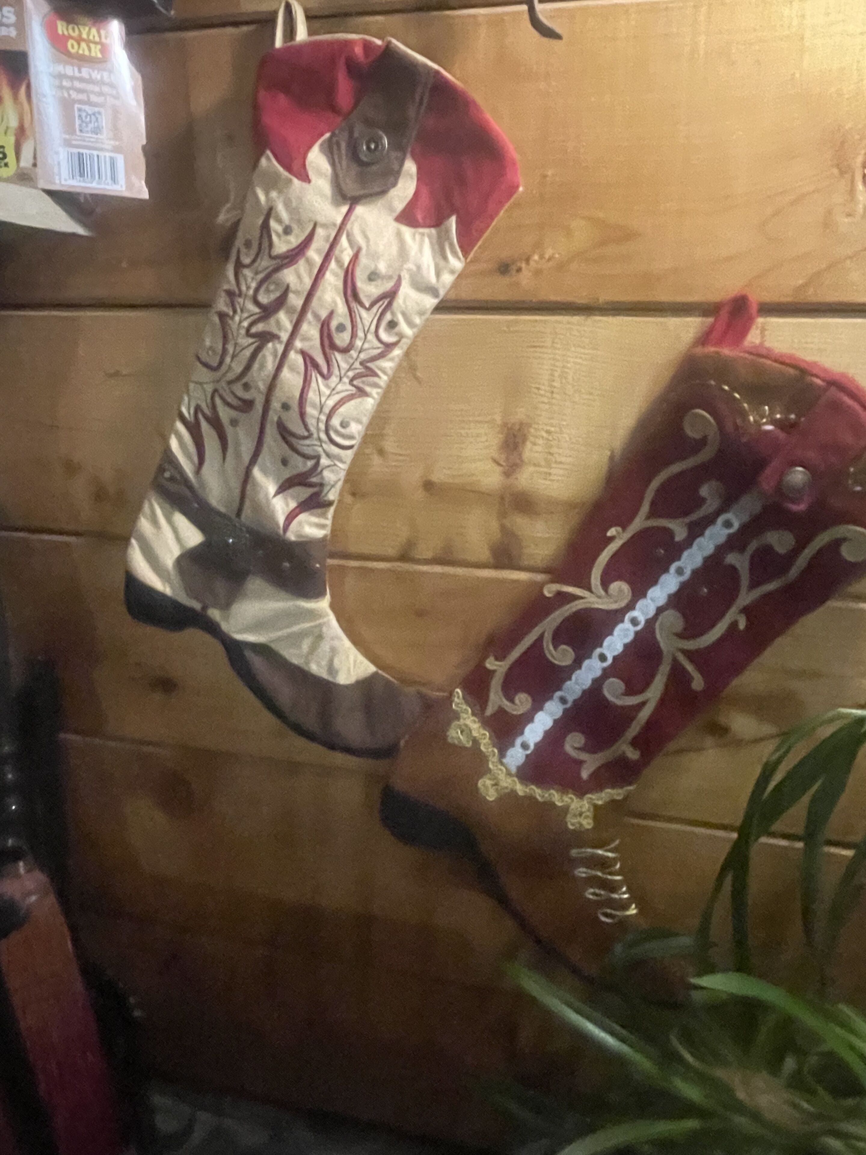 Two decorative boots hanging on a wooden wall.