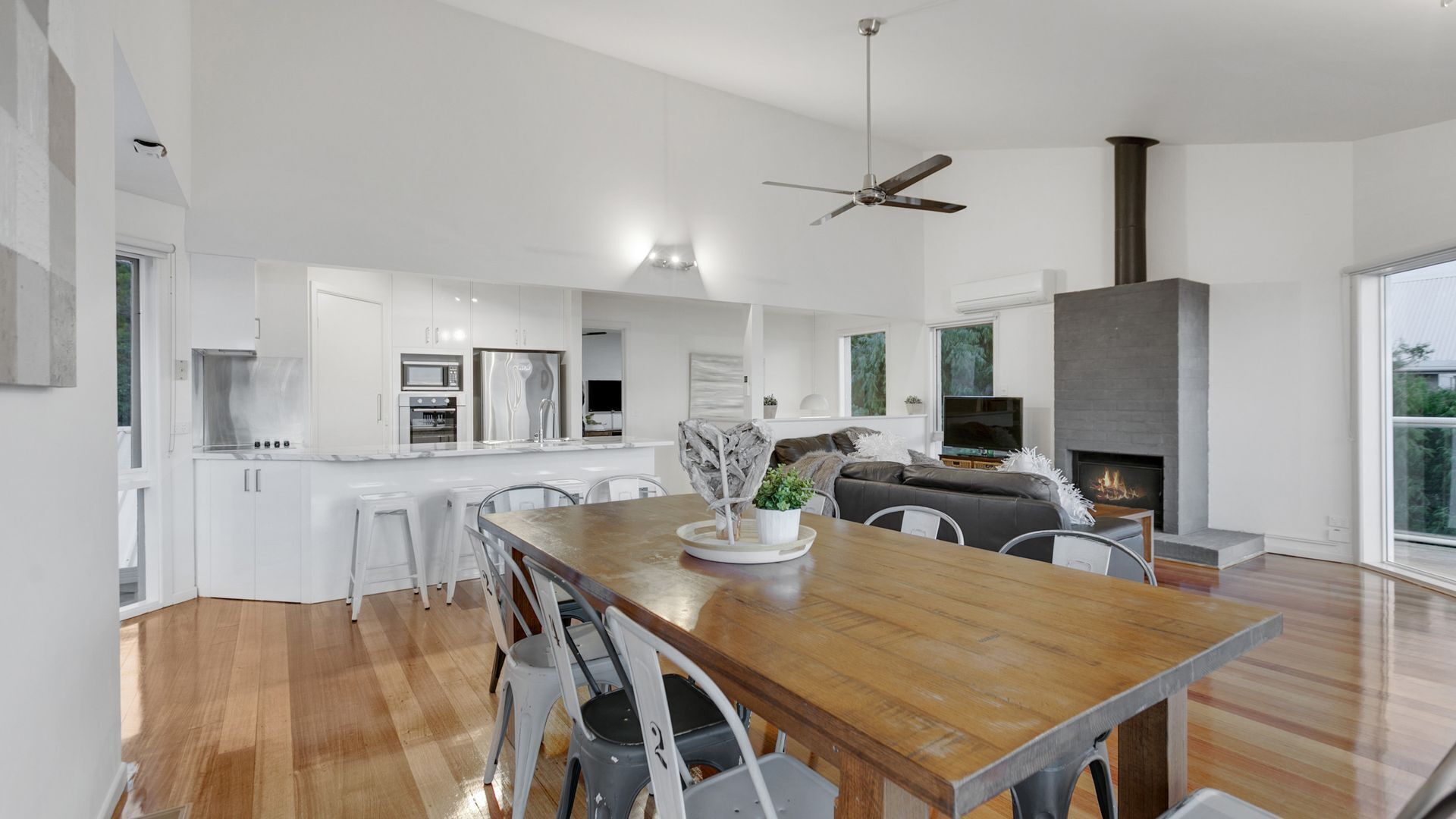 A modern kitchen with white cabinets, a wooden dining table, and a built-in oven.