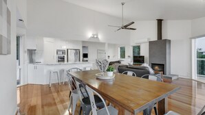 A modern kitchen with white cabinets, a wooden dining table, and a built-in oven.