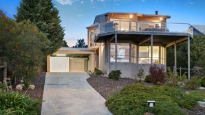 A modern two-story house with a covered patio, a garage, and a well-maintained garden.