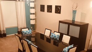 A dining area with a rectangular table surrounded by six chairs, a ceiling fan, and a decorative vase on a cabinet. - Westside El Paso Beautiful Big House lots of Perks contemporary nice Backyard (El Paso)