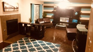 A living room with a fireplace, a sofa, a coffee table, and a TV. - Westside El Paso Beautiful Big House lots of Perks contemporary nice Backyard (El Paso)