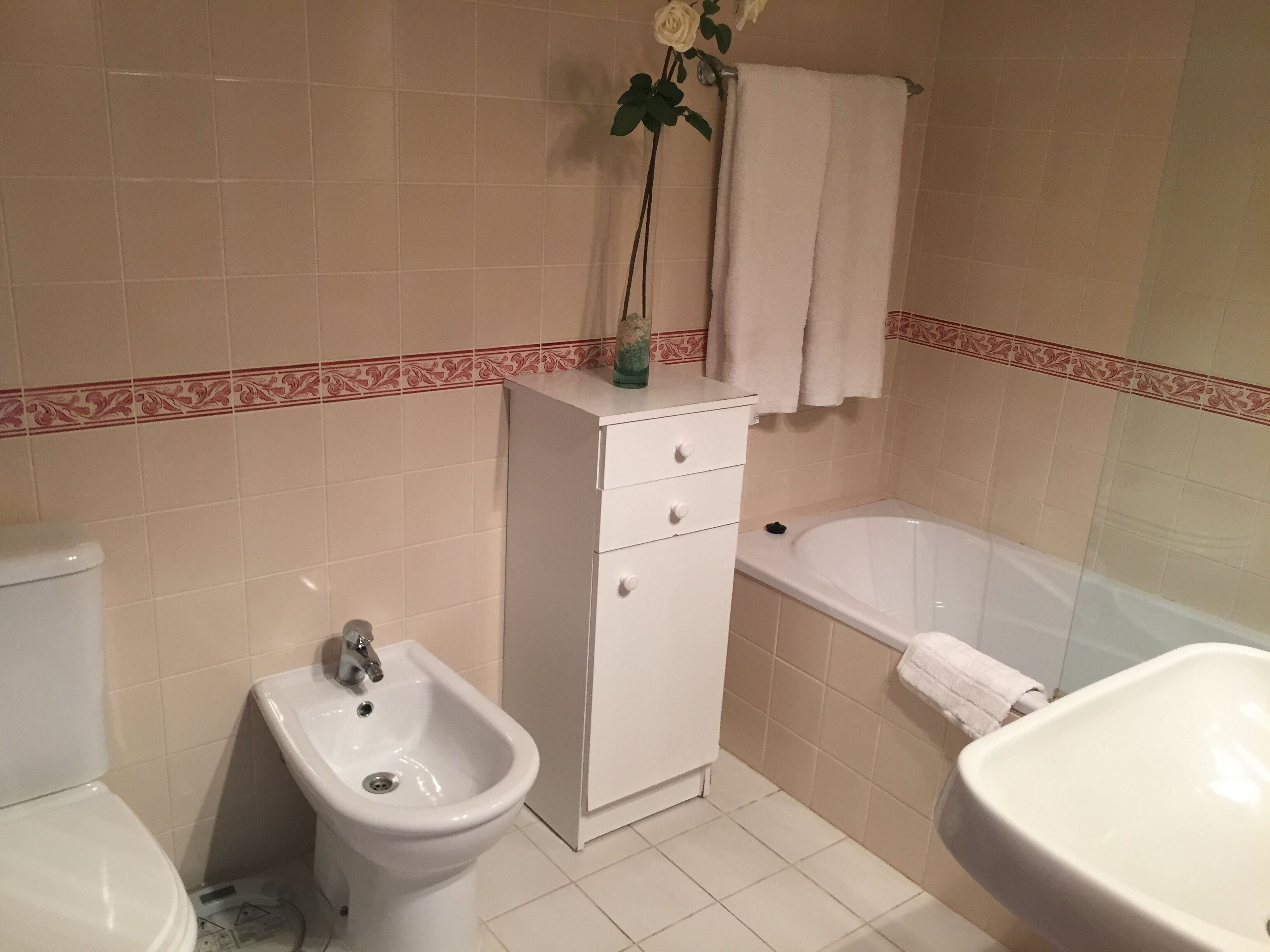 A bathroom with a bidet, toilet, sink, and bathtub.