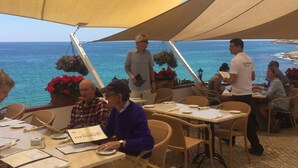 Un espacio al aire libre con mesas y sillas, con vista al mar.
