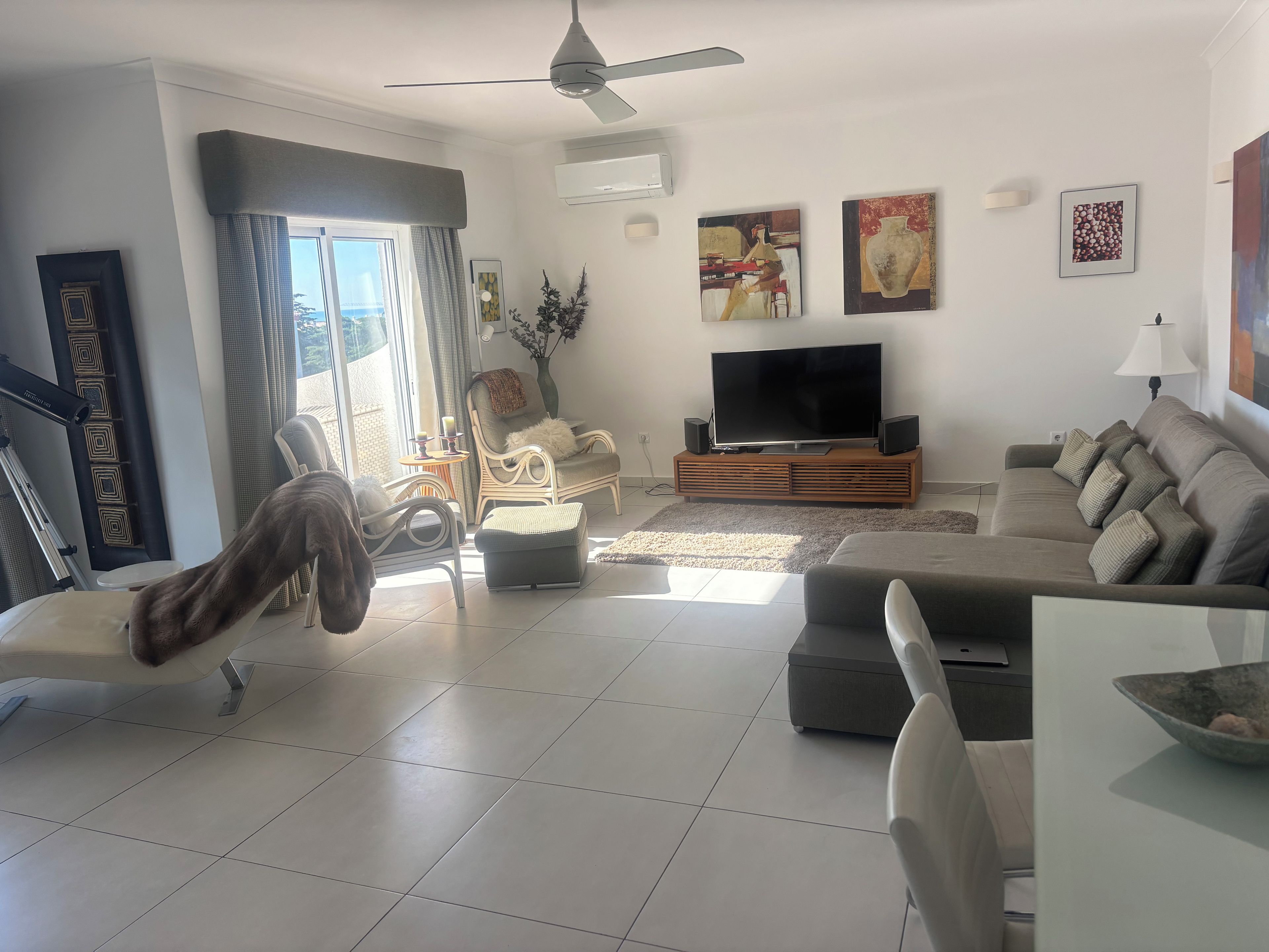 Uma sala de estar moderna com televisão de tela plana, assentos confortáveis e obras de arte nas paredes.