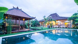 Une piscine avec une terrasse carrelée, des chaises longues et un kiosque.