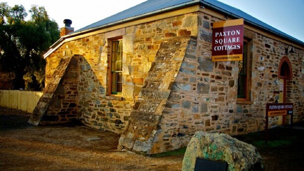 A stone building with a sign reading "Paxton Square Cottages Accommodation." - Paxton Square (Burra)