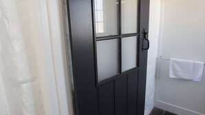 A black door with a frosted glass panel and a white towel hanging on a hook. - Paxton Square (Burra)