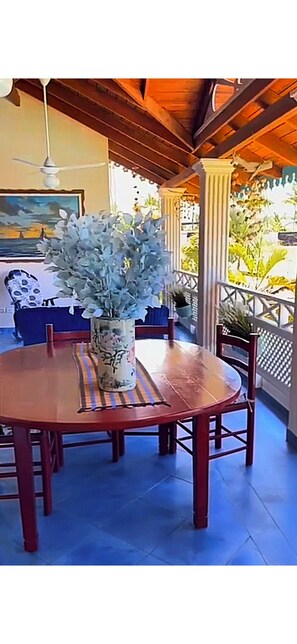 Uma mesa de madeira redonda com cadeiras, um vaso com flores e um quadro na parede.
