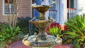 Una fuente de varios niveles con esculturas de aves en un jardín.