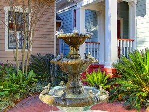Stunning garden fountain surrounded by lush greenery and a classic building with a charming porch.