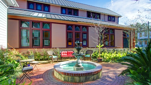 A two-story building with a brick patio, a fountain, and outdoor seating. - Fountain View Cottage, Beautiful Savannah Home (Savannah)