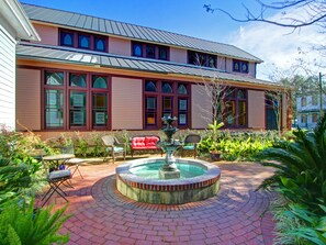 A two-story building with a brick patio, a fountain, and outdoor seating.