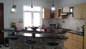 Een moderne keuken met een centraal eiland, barstoelen, een magnetron en een fornuis.