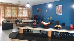 Een moderne woonkamer met een blauwe accentmuur, een grote zwart-wit getoonde salontafel en een zithoek met een bank en fauteuils.