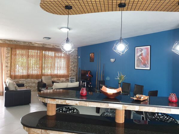 A modern living room with a blue accent wall, a large black and white patterned coffee table, and a seating area with a sofa and chairs.