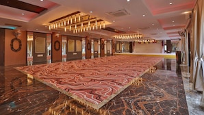 A spacious hotel lobby with a large patterned carpet, marble flooring, and modern lighting fixtures. - Hotel President Cottage Resort (Jalgaon)