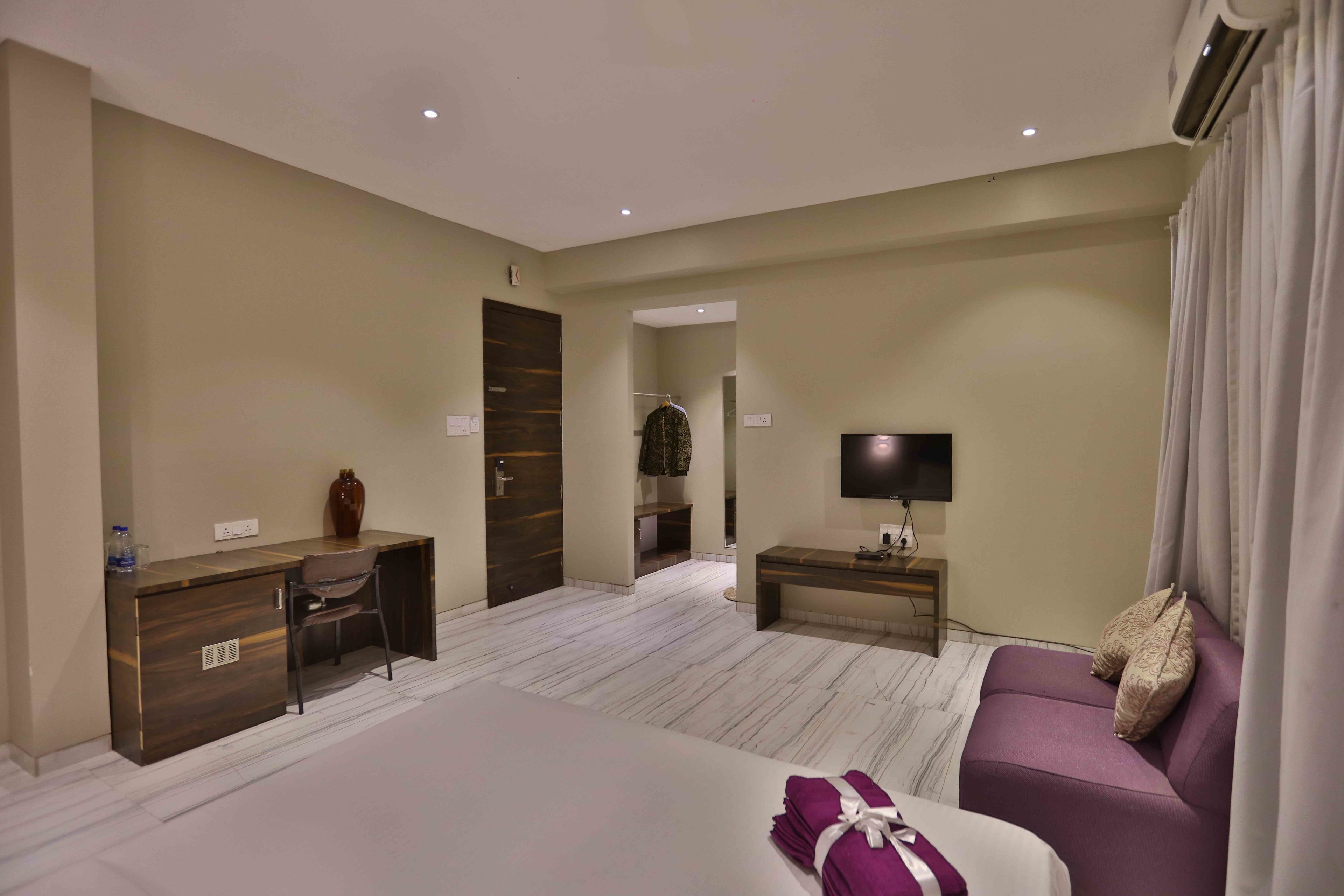 Habitación de hotel con cama, escritorio, silla, televisor y sofá.