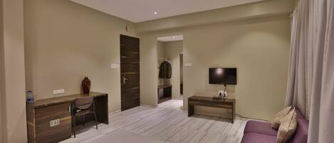Habitación de hotel con cama, escritorio, silla, televisor y sofá.