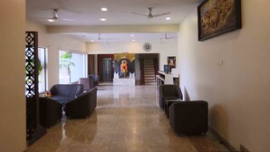 A hotel lobby with seating areas, a reception desk, and a staircase leading to another floor. - Hotel President Cottage Resort (Jalgaon)