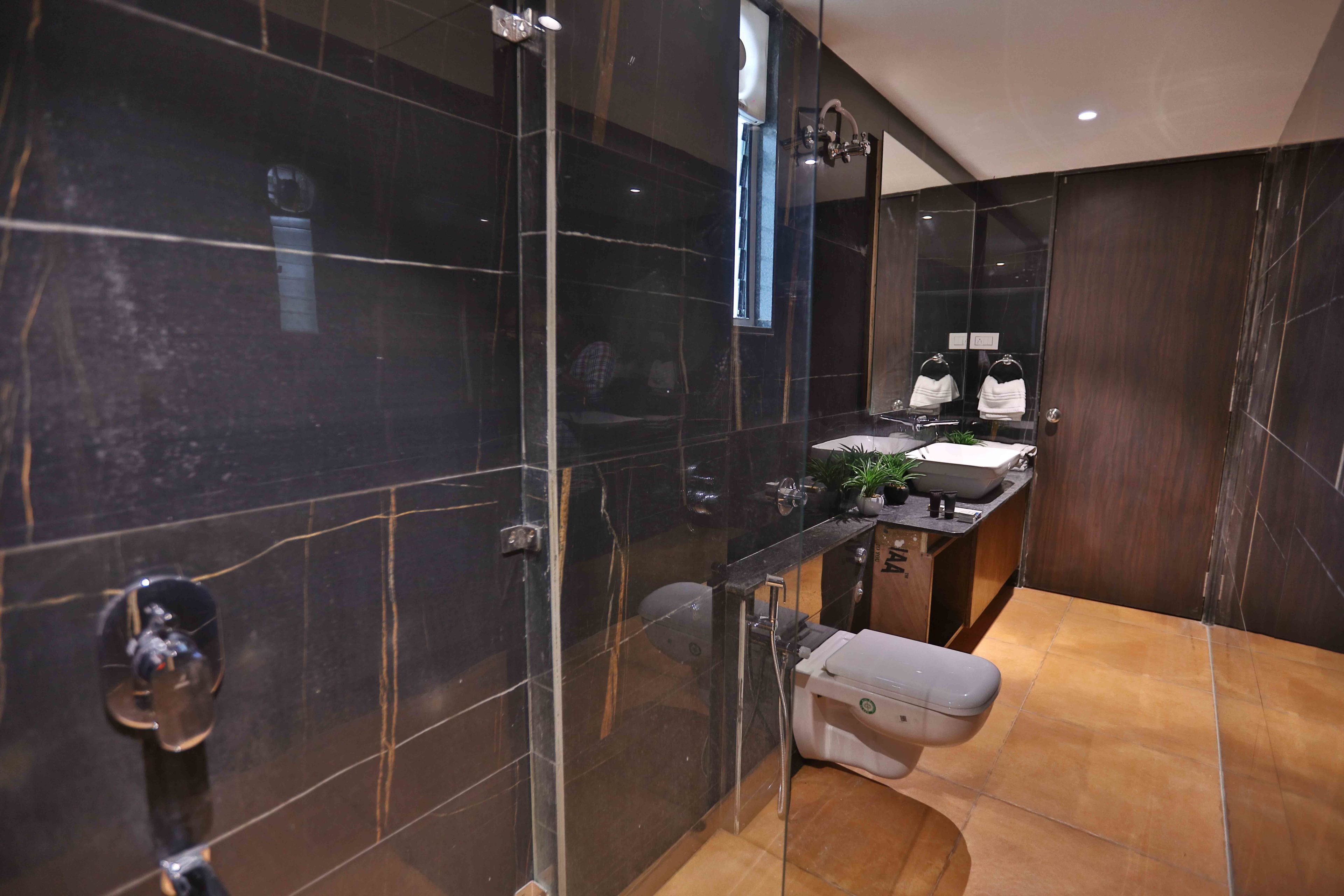 A modern bathroom with a glass shower enclosure, a toilet, and a sink area with a mirror and towel rack.