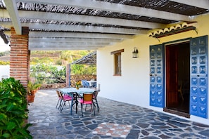 A patio with a table and chairs, a brick pillar, and a blue door. - Country Home with Pool, Patio and Panoramic Views (Frigiliana)