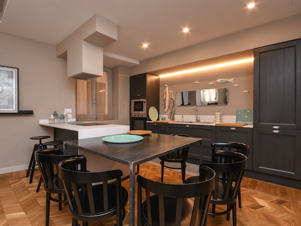 Una cocina moderna con una isla central, un área de comedor con sillas y un espejo grande sobre el lavamanos.