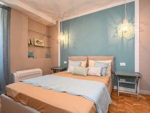 Un dormitorio con cama, mesitas de noche, una lámpara de pared y un calentador.