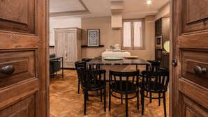 A dining area with a wooden table and chairs, a cabinet, and a microwave in the background. - Modern Apartment by the Lake (SALO)